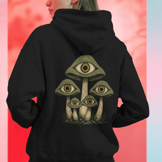 Model wearing a black hoodie with mystical eye-covered mushrooms printed on the back, surreal psychedelic streetwear design.