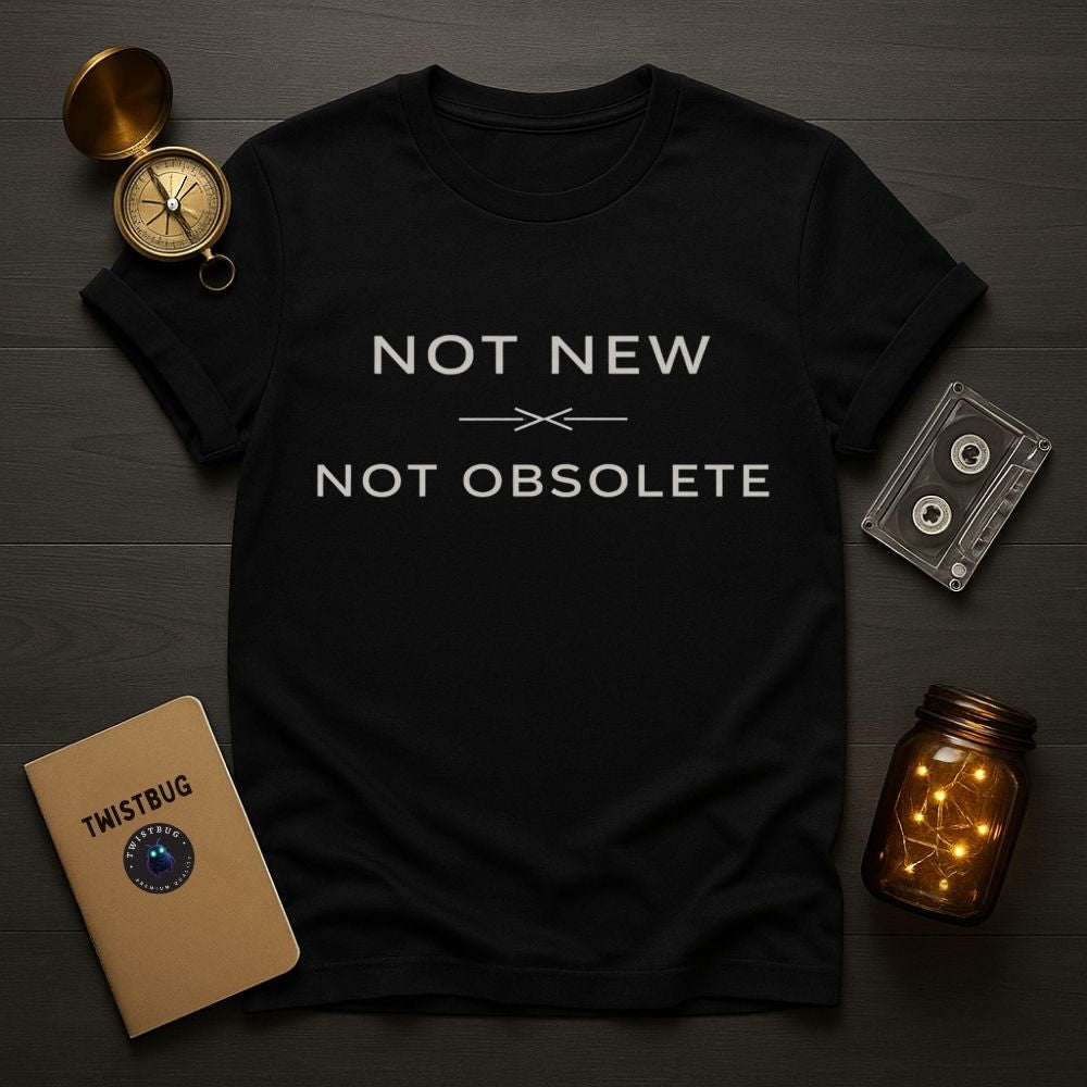 Black t-shirt with 'Not New Not Obsolete' text on a wooden surface with vintage items.