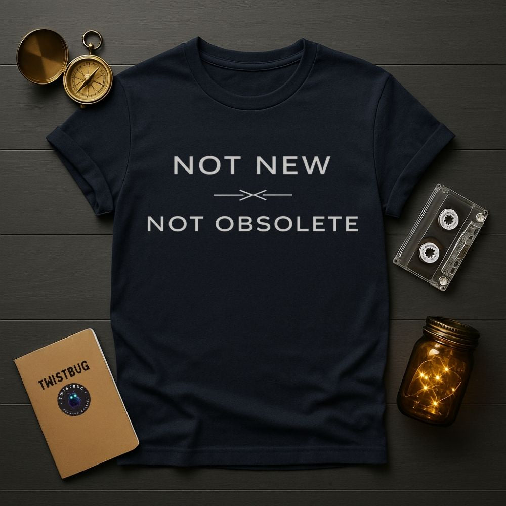 Navy blue t-shirt with 'Not New Not Obsolete' text on a wooden surface with vintage items.