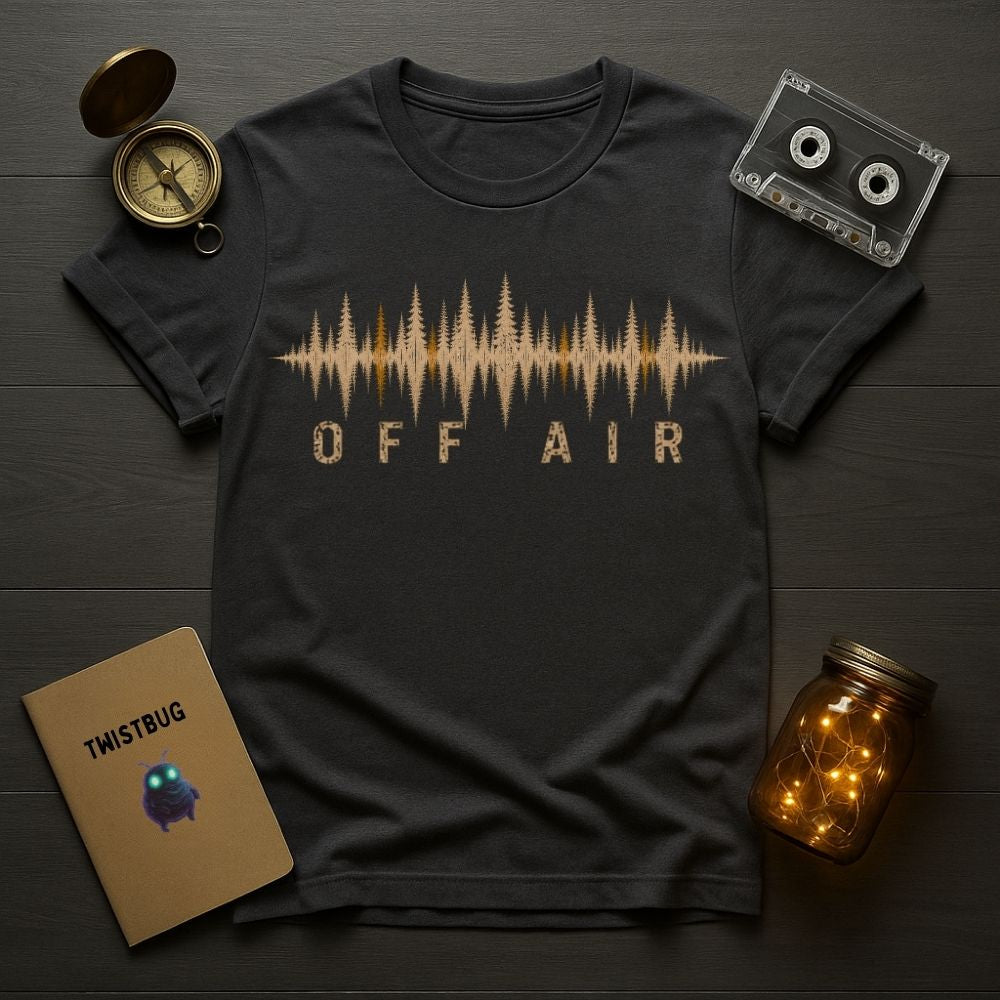 Black t-shirt with 'OFF AIR' design on a wooden surface with a compass, cassette tape, and jar.