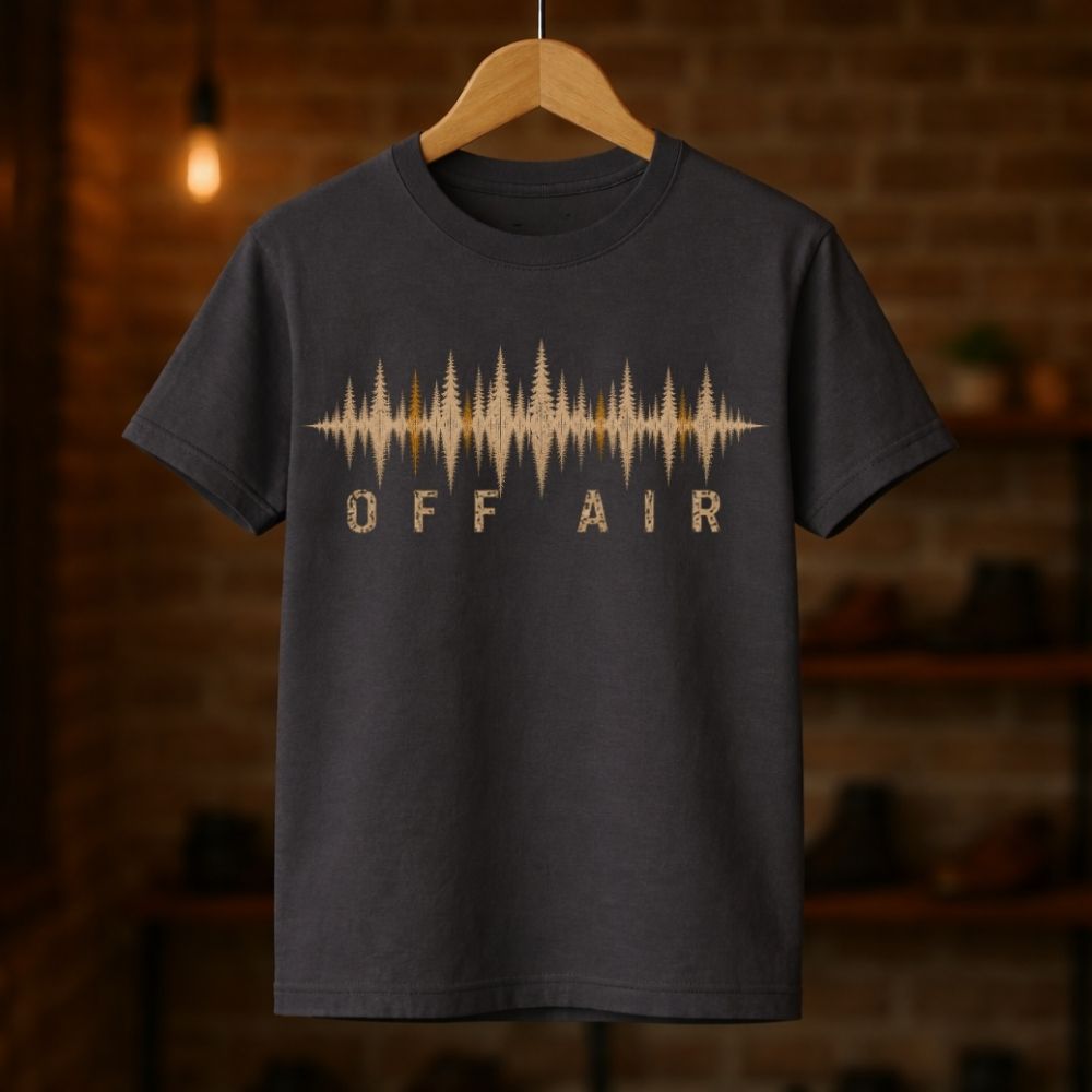 Black t-shirt with 'OFF AIR' design on a wooden hanger against a brick wall background