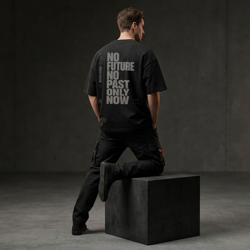 Person wearing a black t-shirt with text sitting on a black block against a dark background