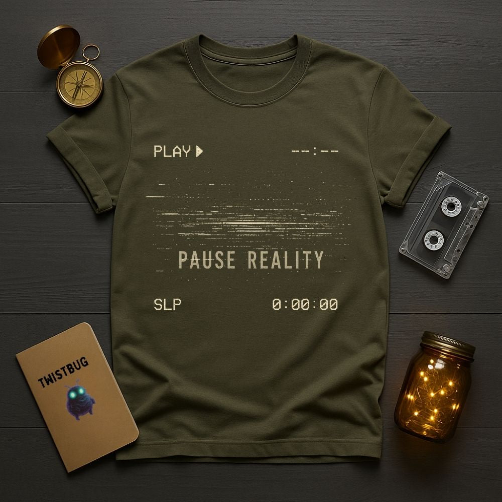 Green t-shirt with 'Play Pause Reality' text on a wooden surface with vintage items.