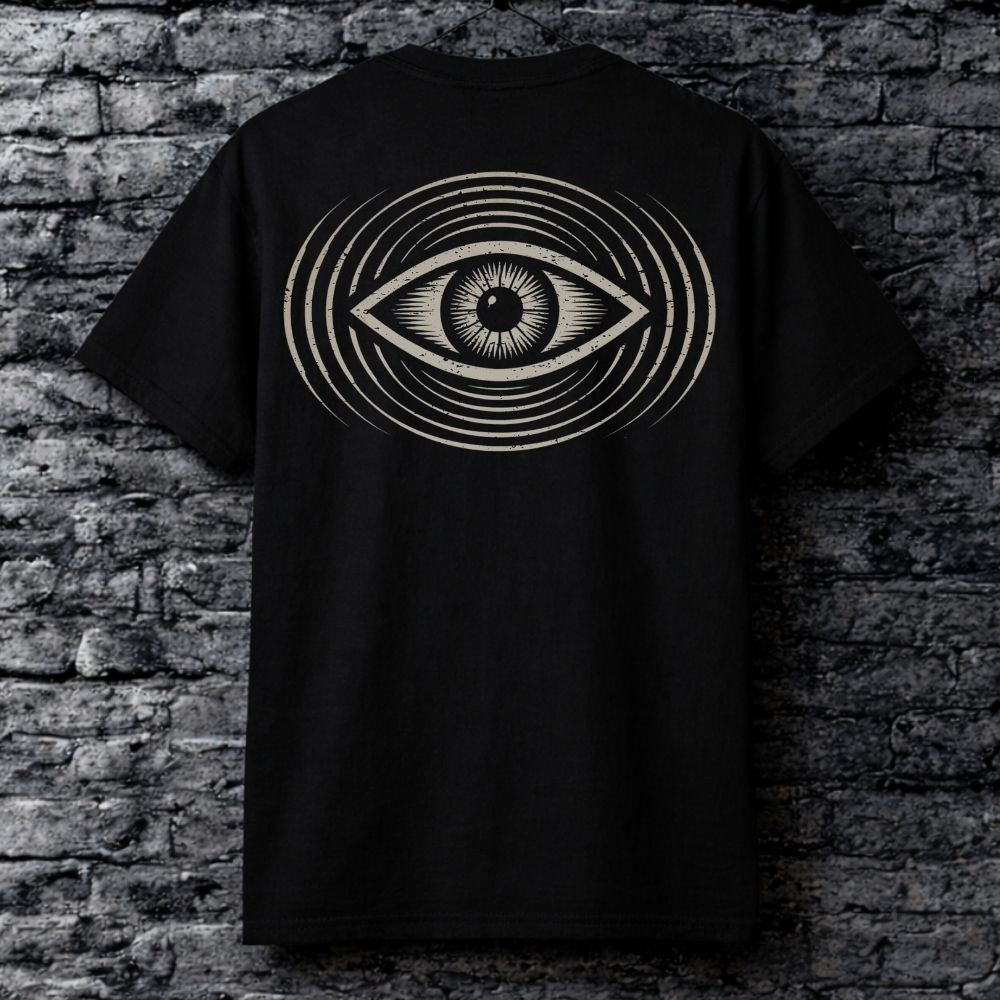 Black t-shirt with an eye design on the back against a brick wall.