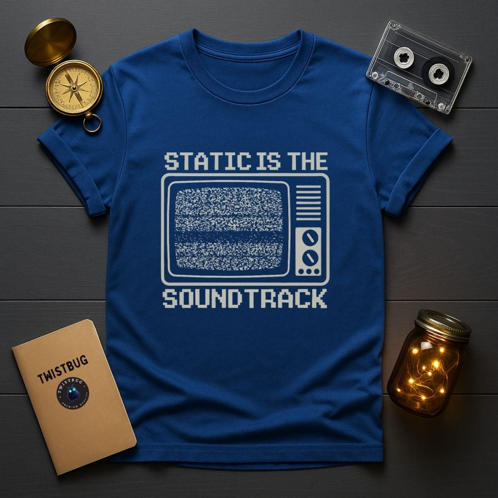 Blue graphic tee flat lay with retro media props and TV static print
