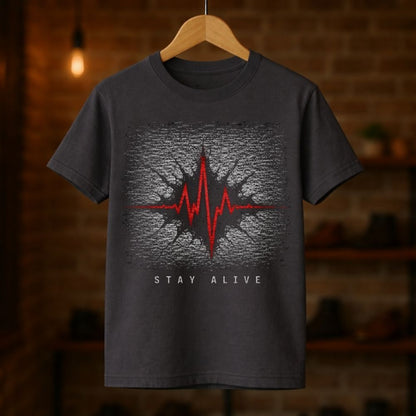 Dark gray t-shirt with a heart rate design and 'Stay Alive' text on a wooden hanger against a blurred brick wall background.