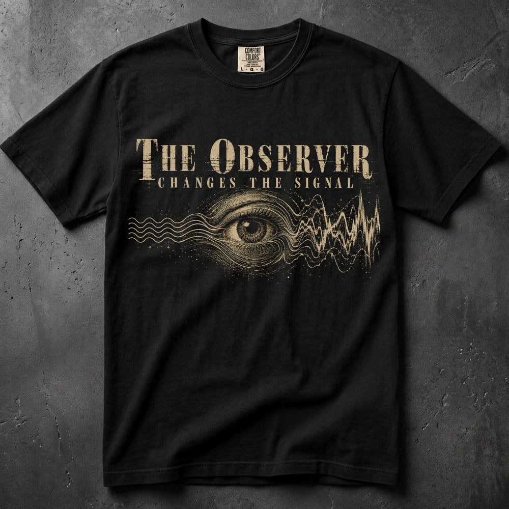 A black short-sleeve graphic t-shirt laid flat on a dark textured background. The shirt features a distressed gold graphic of a human eye with soundwave lines and the text 'THE OBSERVER CHANGES THE SIGNAL'.