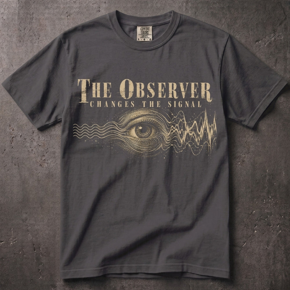 A dark gray crewneck t-shirt featuring a gold graphic print of an all-seeing eye, sound waves, and the text 'THE OBSERVER CHANGES THE SIGNAL'. The shirt is laid flat on a textured gray background.