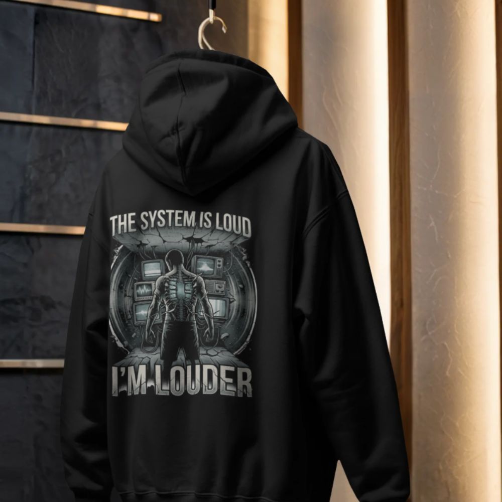 Black hoodie hanging on hook showing “The System Is Loud I’m Louder” dystopian cyberpunk back print