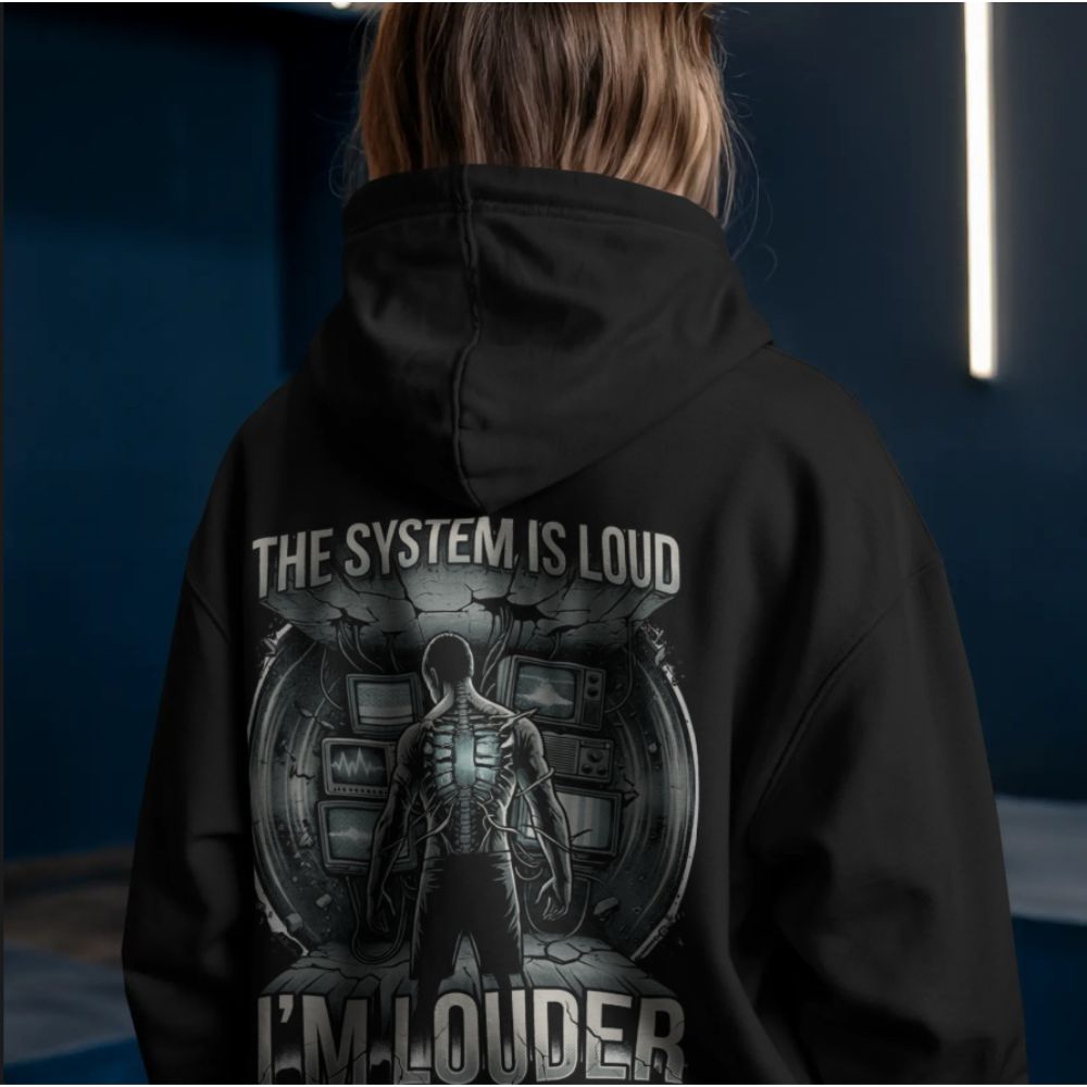 Model wearing black hoodie with “The System Is Loud I’m Louder” cyberpunk graphic on the back, dystopian tech resistance design