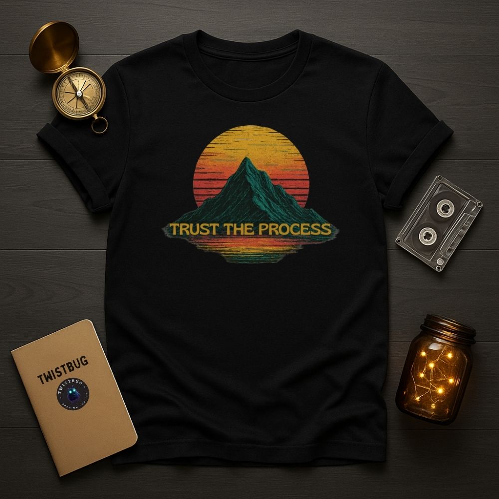 Black “Trust the Process” T-shirt with retro mountain sunset, flat lay with cassette and notebook.