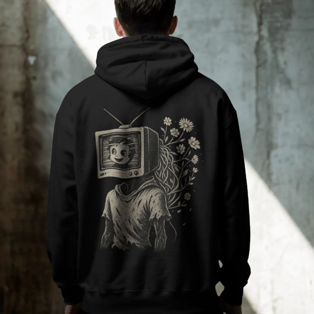 Black hoodie worn outdoors featuring a surreal TV-head figure with flowers growing from the body, symbolizing analog nostalgia and inner growth