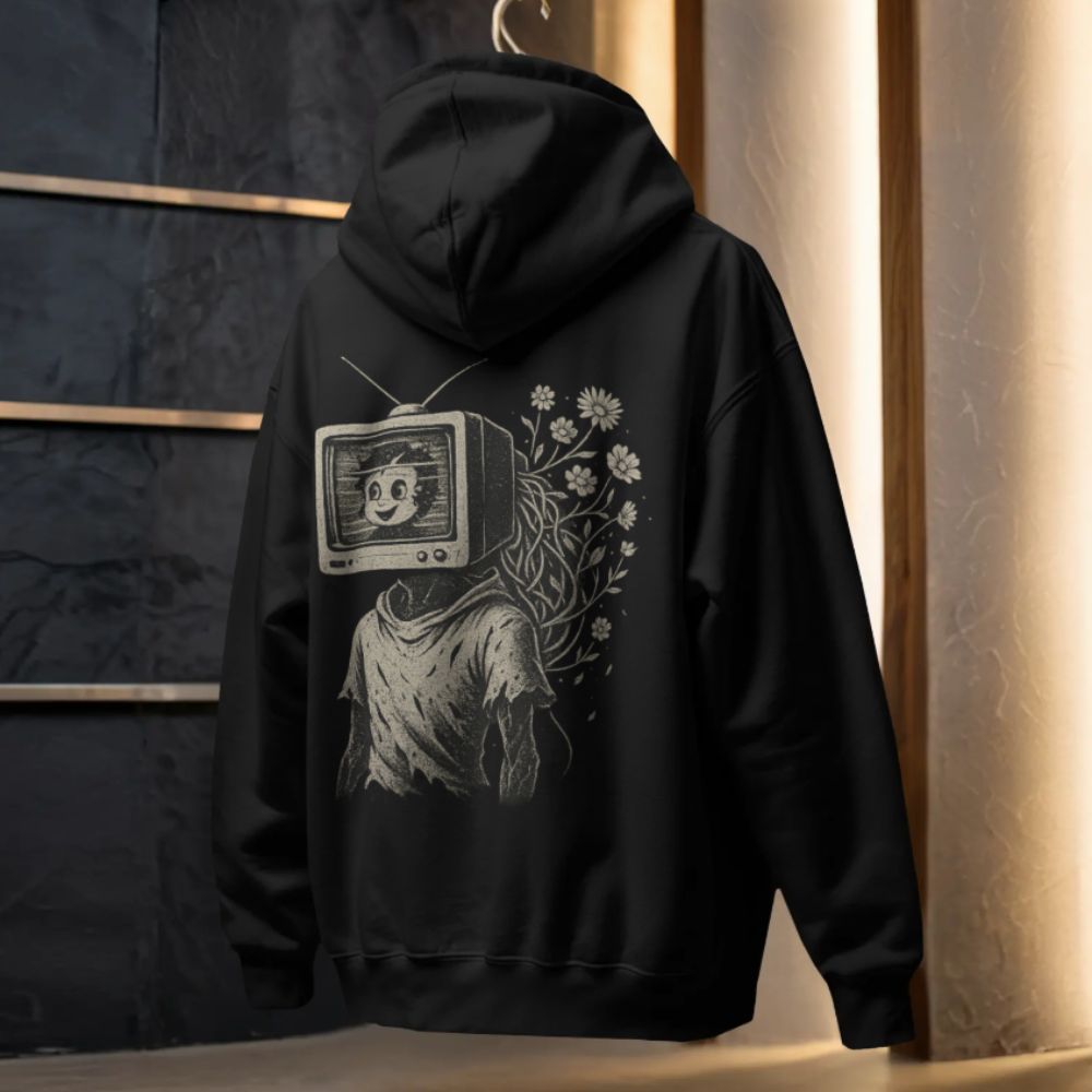 Black hoodie hanging indoors with a vintage TV-head character illustration and floral elements on the back