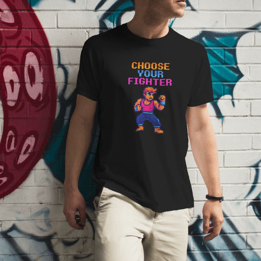 Man wearing “Choose Your Fighter” T-shirt standing by graffiti wall, streetwear gaming look.