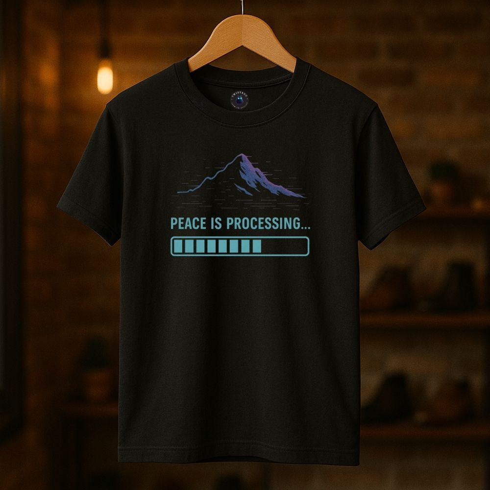 Black Twistbug T-shirt on hanger showing “Peace Is Processing” mountain design and glowing loading bar, warm boutique lighting.