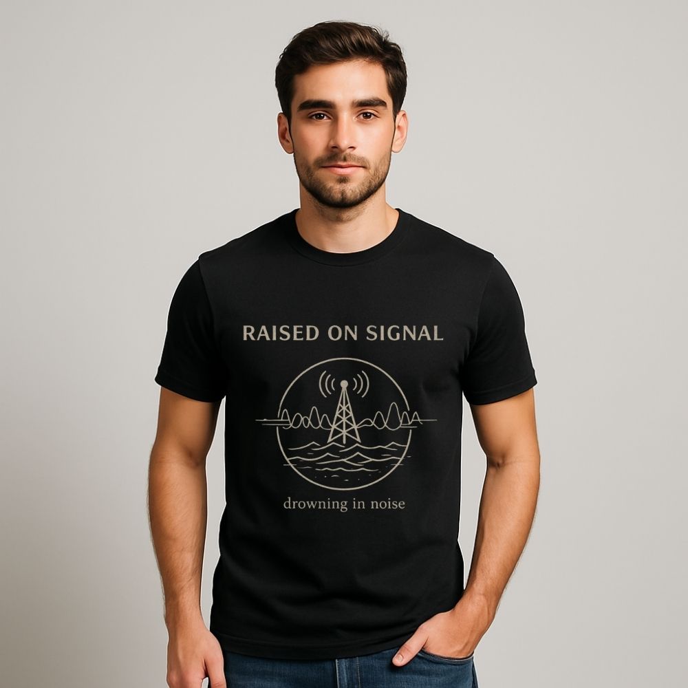 Man wearing a black t-shirt with 'Raised on Signal' design on a plain background