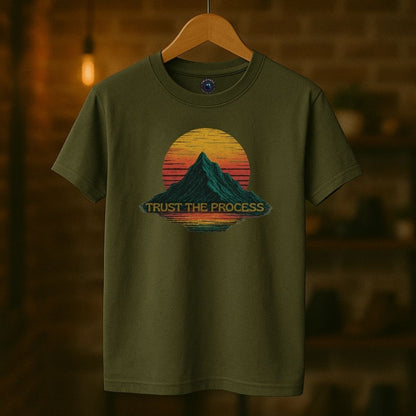 Military green Twistbug T-shirt on hanger displaying “Trust the Process” graphic with mountain silhouette and retro sun.