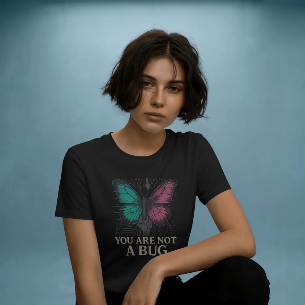 Woman wearing black “You Are Not a Bug” T-shirt featuring a cyber butterfly design, blue minimalist studio backdrop.