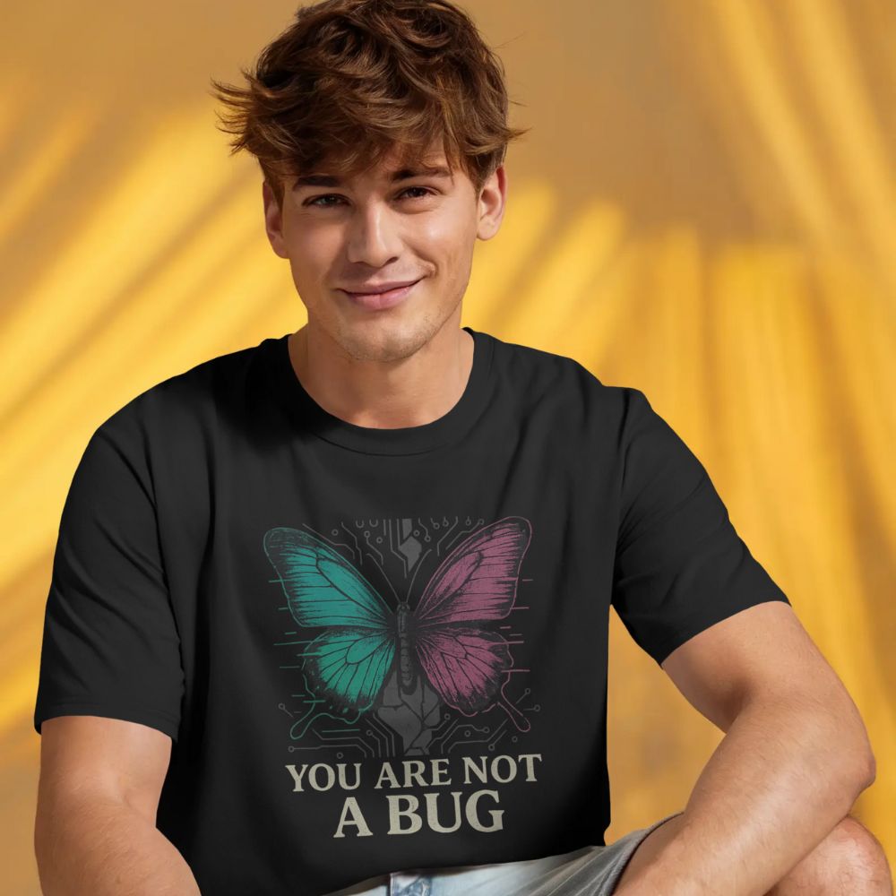 Man wearing black “You Are Not a Bug” T-shirt with glitch butterfly art, warm yellow studio lighting.