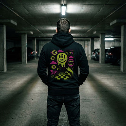 Back view of a black hoodie with neon surreal smiley and eye graphics worn in a dim parking garage