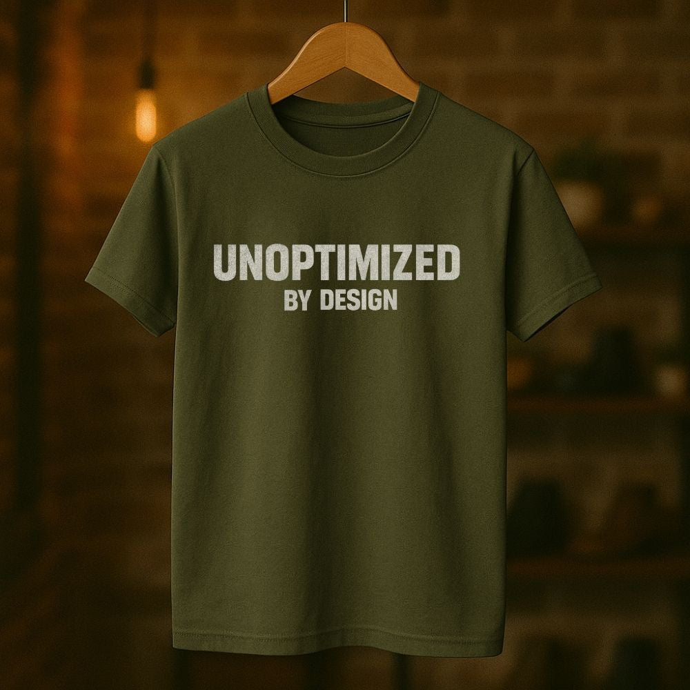 Green t-shirt with 'UNOPTIMIZED BY DESIGN' text on a wooden hanger against a blurred background