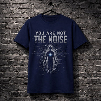 A navy blue graphic t-shirt hanging on a black hanger against a dark gray brick wall. The shirt features a distressed white text graphic reading 'YOU ARE NOT THE NOISE' above a glowing blue digital human silhouette.